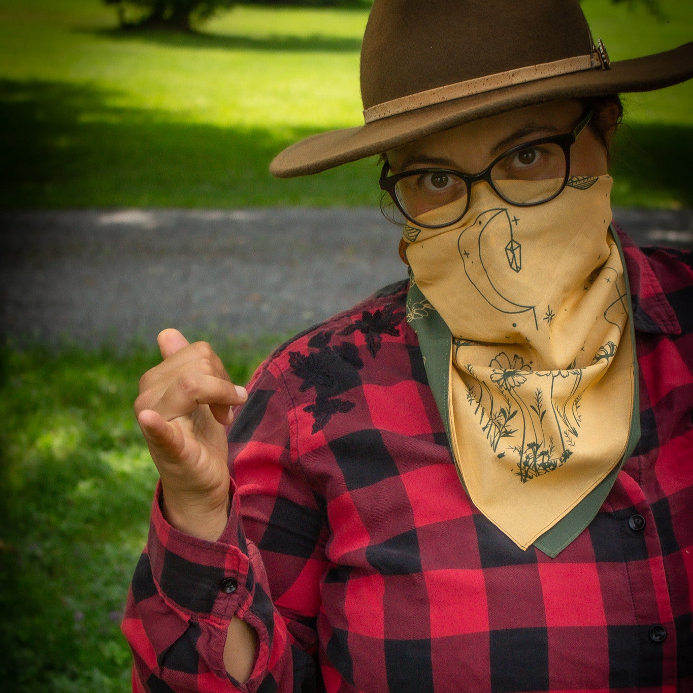 woman in red plaid with yellow bandana crescent moon covering her face
