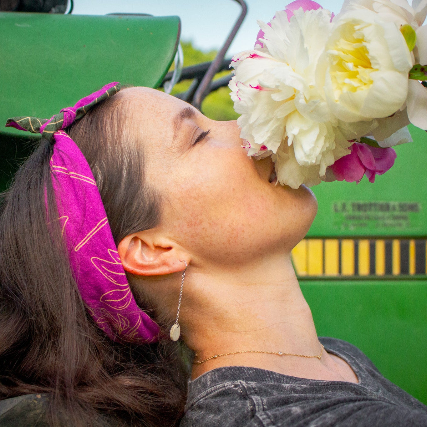 wild clover pink bandana on woman with darling wild earrings smelling peonies