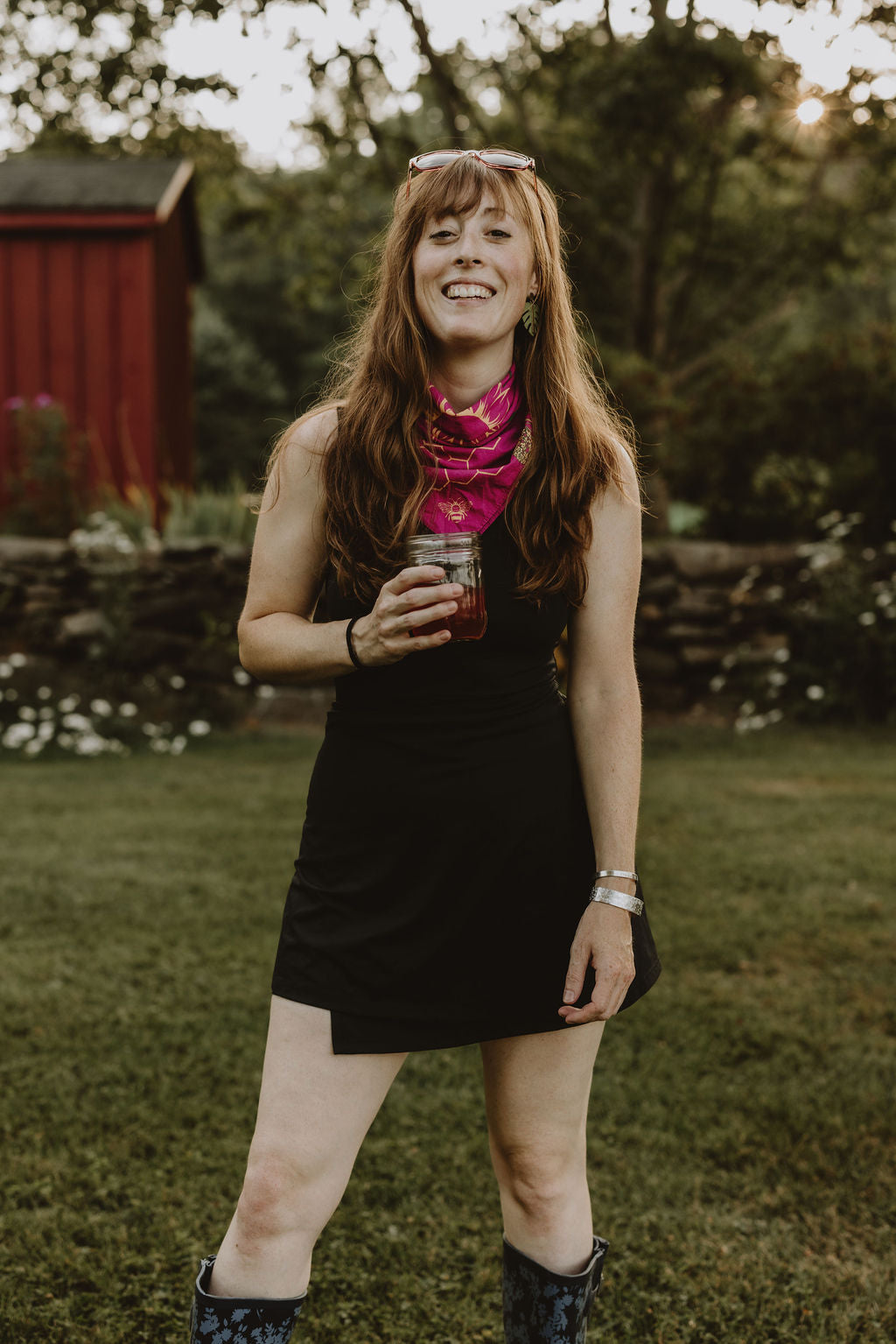 CARA GOODENOUGH standing in yard with glass jar and black dress