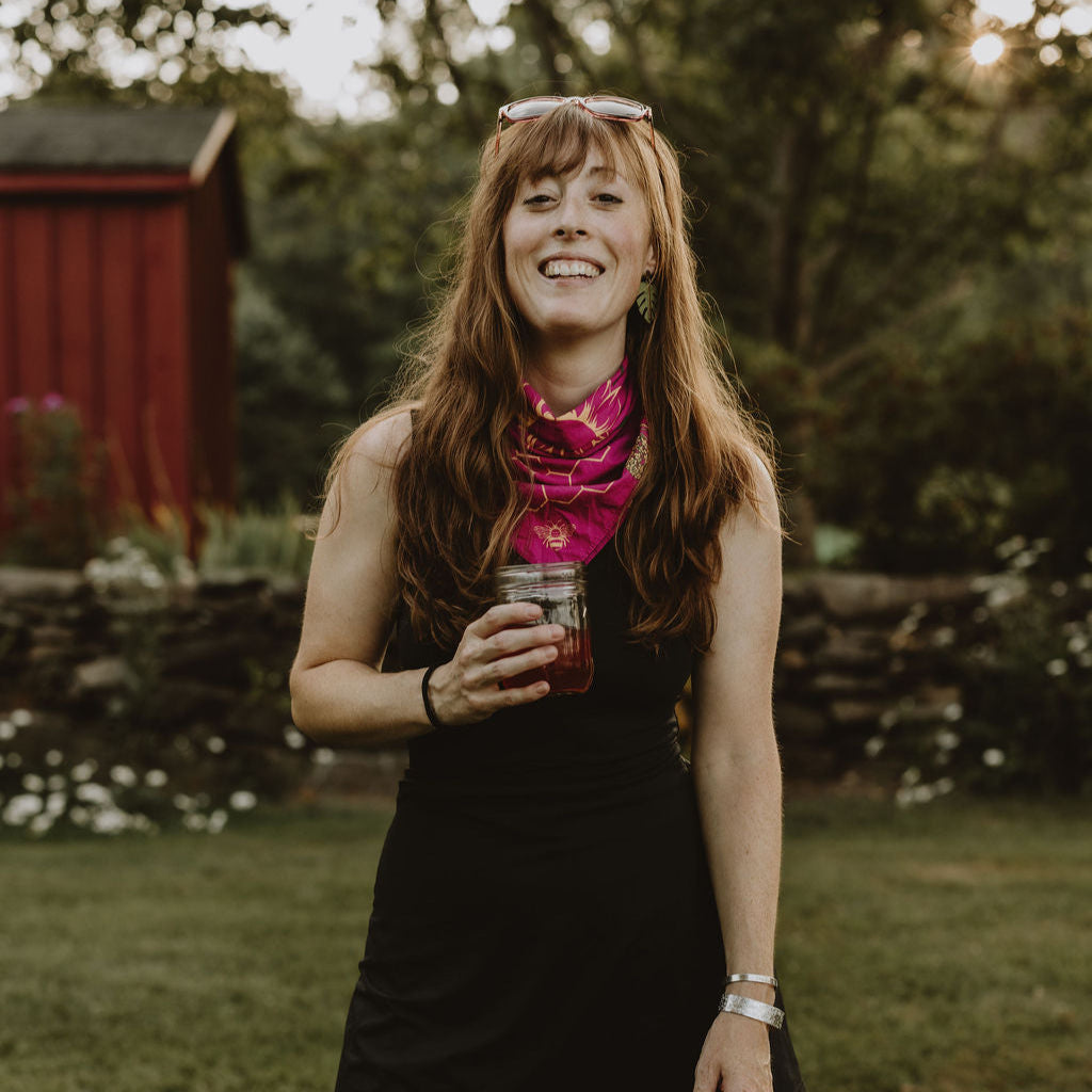 CARA GOODENOUGH standing in yard with glass jar and black dress