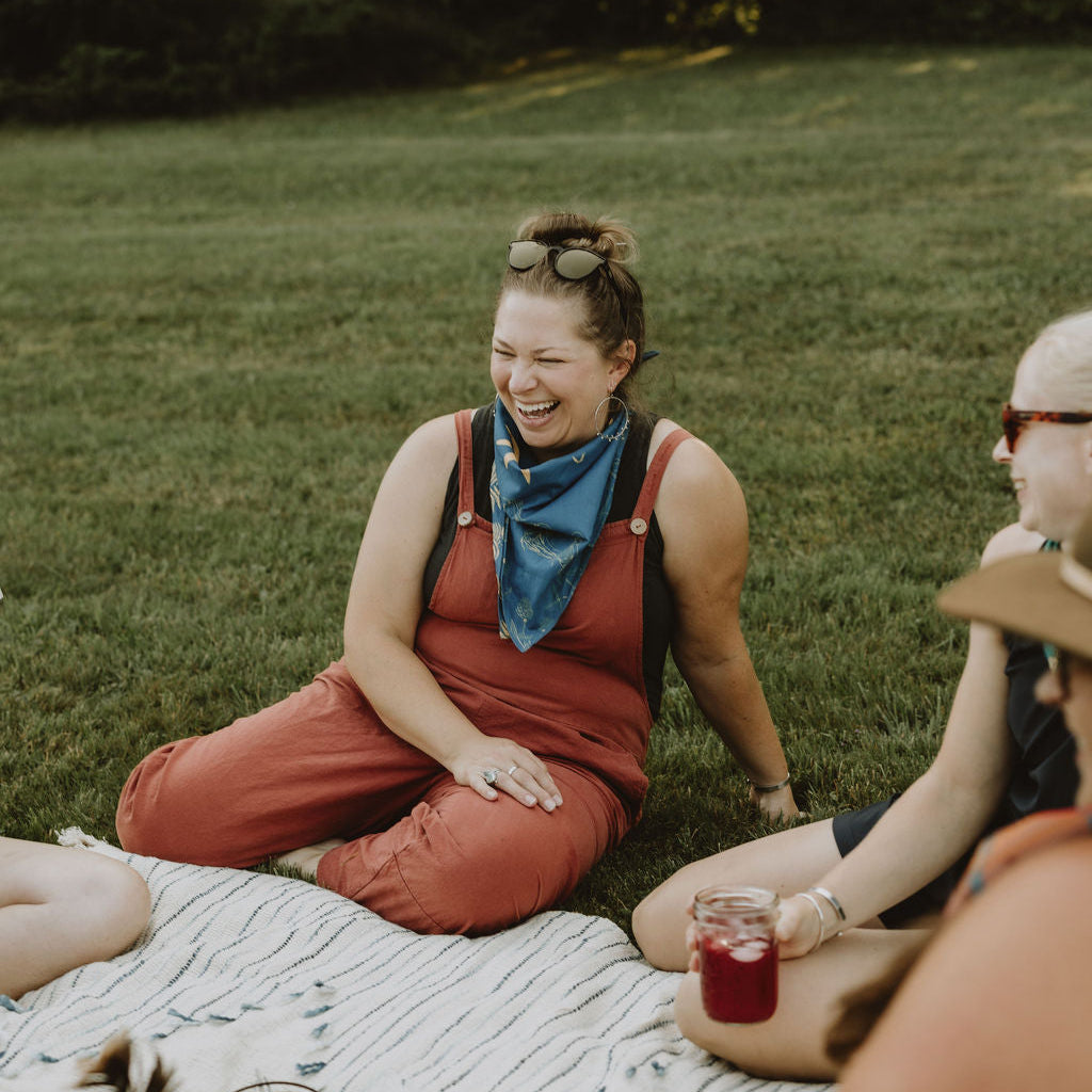 woman laughing outside with blue bandana on her neck and sunglasses on her head