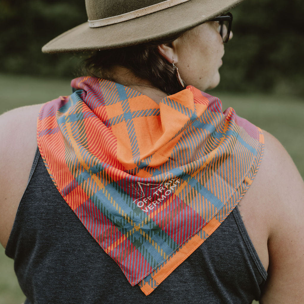 Person wearing an orange plaid scarf and hat outdoors